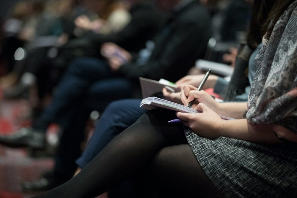 Photo by The Climate Reality Project selective focus photography of people sitting on chairs while writing on notebooks